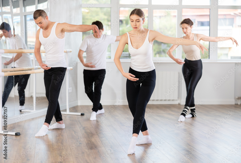 Obraz premium Graceful woman confidently leading ballet class with male and female amateur dancers following her movements in spacious serene dance studio ..