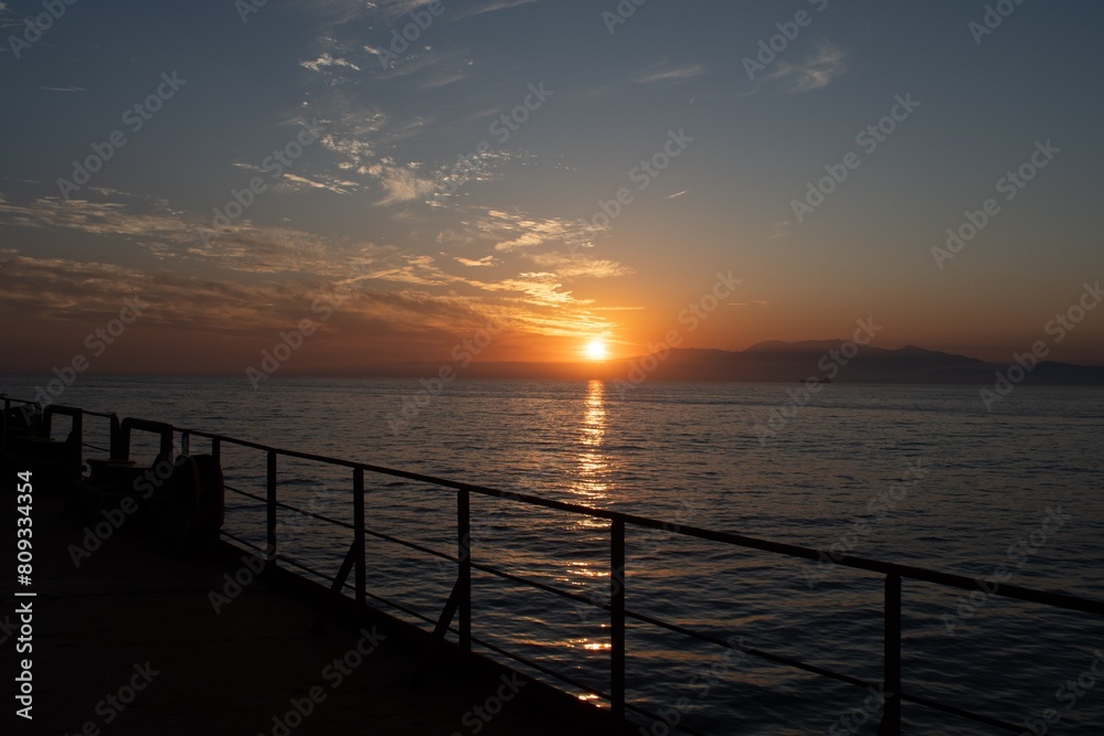 sunset view over the coastline from the deck of a cargo ship
