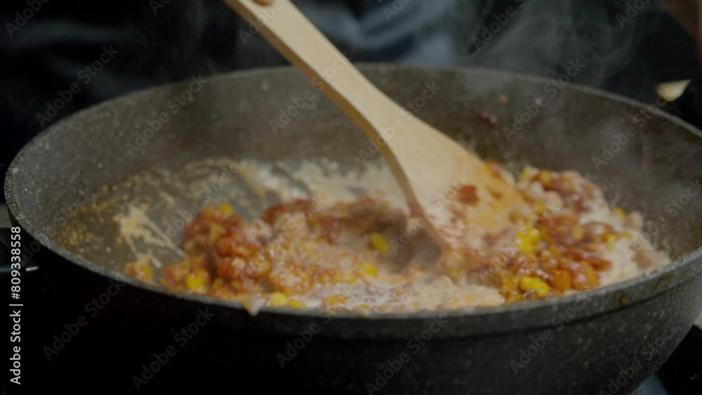Immerse yourself in the world of cooking as you watch a skilled chef mix chicken with corn in a curry sauce using a wooden spoon. Admire the graceful movements and precise technique as they create a Immerse yourself in the world of cooking as you watch a skilled chef mix chicken with corn in a curry sauce using a wooden spoon. Admire the graceful movements and precise technique as they create a