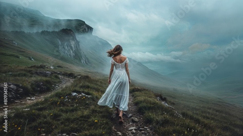 Beautiful young woman in white dress walking in the mountains on a cloudy day