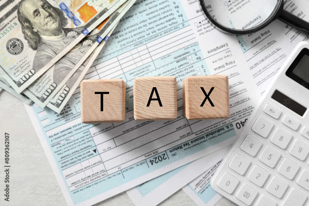 Fototapeta premium Wooden cubes with word Tax, documents, money and calculator on light table, flat lay