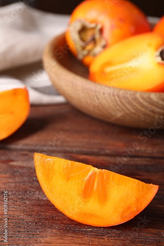 Piece of delicious ripe persimmon on wooden table, closeup