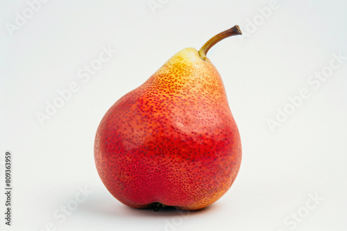 a red pear with a yellow stem on a white surface