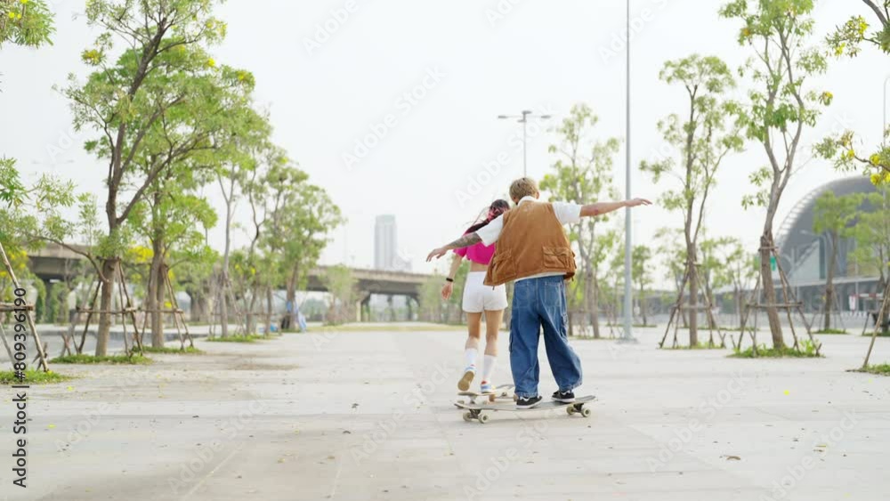 Group of Young Asian man and woman friends skating on longboard skate at public park on summer vacation. Stylish people have fun urban lifestyle practicing outdoor sport skateboarding at city street. Group of Young Asian man and woman friends skating on longboard skate at public park on summer vacation. Stylish people have fun urban lifestyle practicing outdoor sport skateboarding at city street.