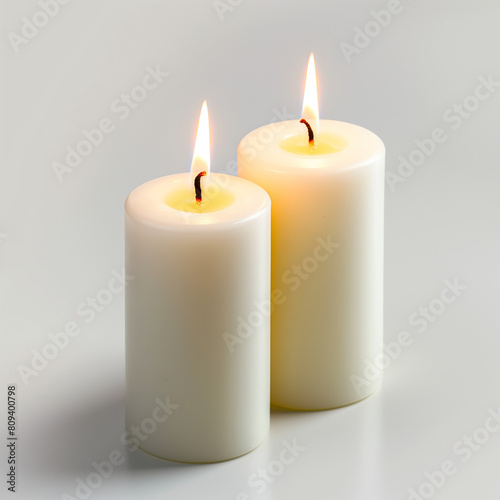 two white candles are lit on a white surface