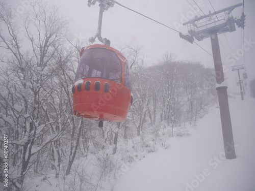 Ski lift cabin with people in the snowfall in mountains
