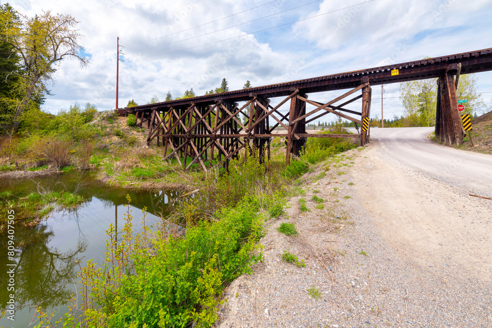 A trestle bridge supporting train tracks above Kent Creek, alongside a gravel road near the Pend Oreille River in the rural small town of Newport, Washington State, USA. A trestle bridge supporting train tracks above Kent Creek, alongside a gravel road near the Pend Oreille River in the rural small town of Newport, Washington State, USA.