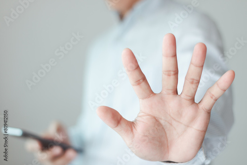 Closeup of the hand of a businessman showing stop, saying no or not accepting a deal in an office at work. Male corporate workers make hand gestures not agree to a statement or refuse.
