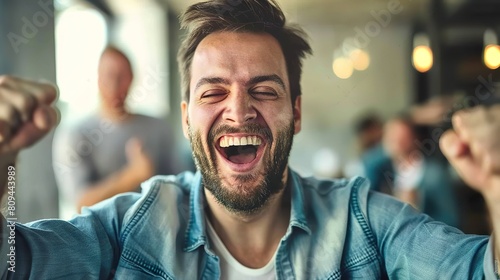 Portrait of a young man laughing while taking a selfie in a cafe