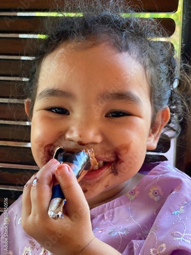 Portrait of cute little Asian girl eating ice cream, closeup of her face