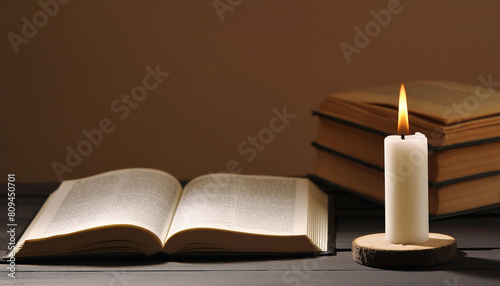 A candle burns next to an open Bible