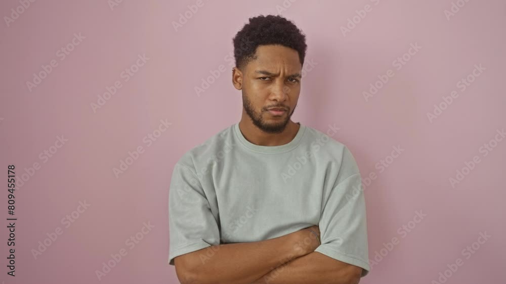 Unimpressed african american man wearing t-shirt stands frowning, upset by problem on isolated pink backdrop, showcasing negative, skeptical and nervous vibe!