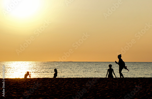 Silhouette of people relax on beach with sunset sky background