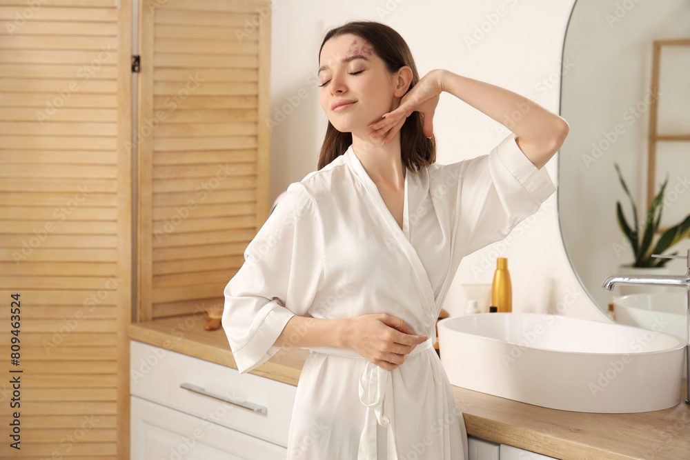 Young woman doing face building exercise in bathroom Young woman doing face building exercise in bathroom