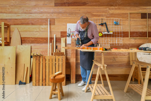 Mature carpenter sawing woo...