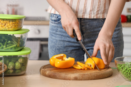 Woman cutting bell pepper for freezing in kitchen, closeup