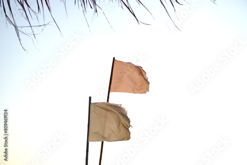 Old flag with blue sky, Sign for warning at beach