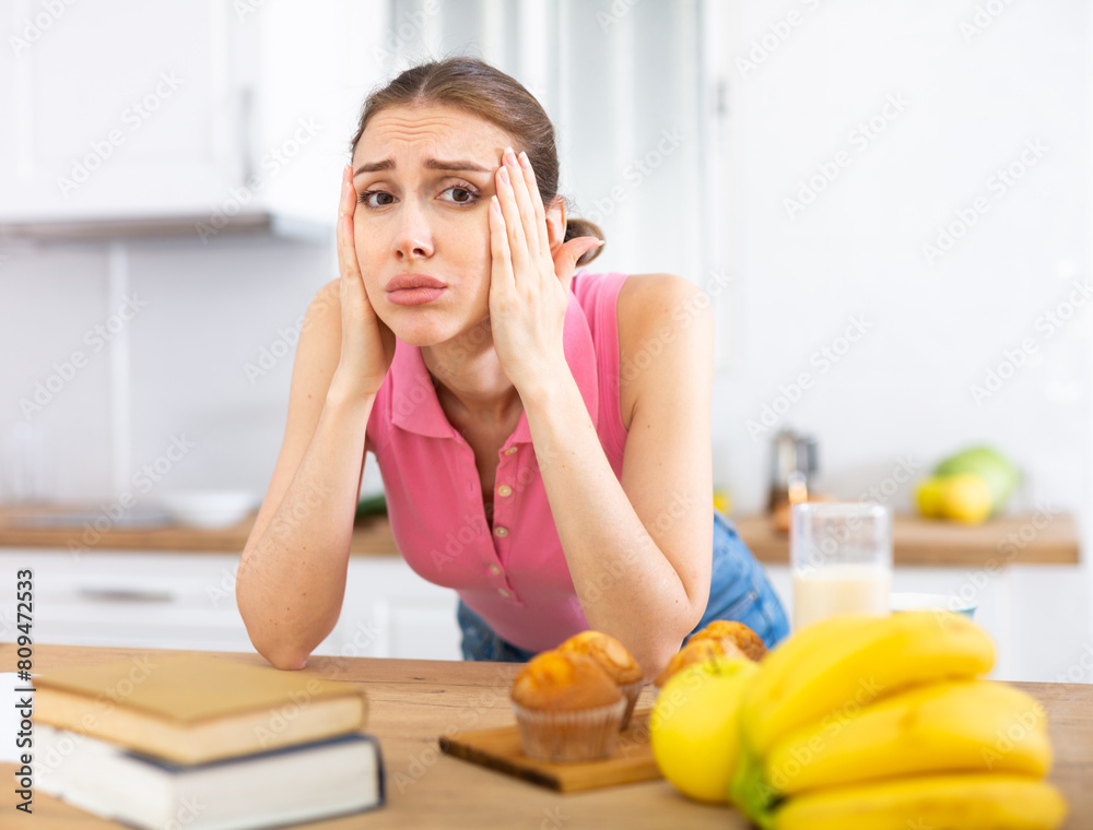 Housewife suffering from headache while preparing breakfast in kitchen Housewife suffering from headache while preparing breakfast in kitchen
