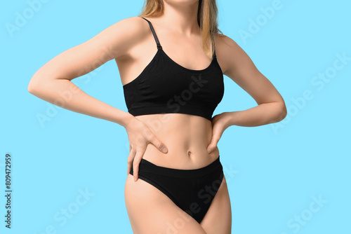 Sexy young woman in black cotton underwear on blue background