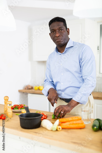 Man from AMERICA in an apron is preparing to cut vegetables in the kitchen to prepare soup