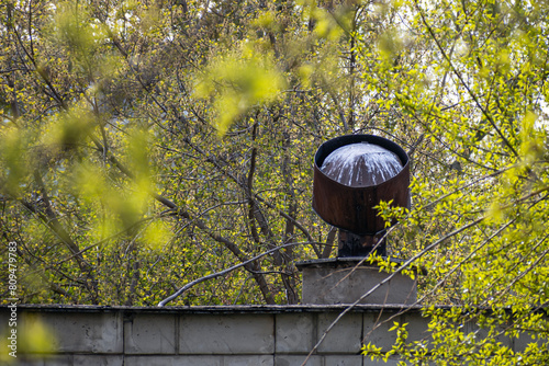 Ventilation pipe on the roof of the building on a spring day