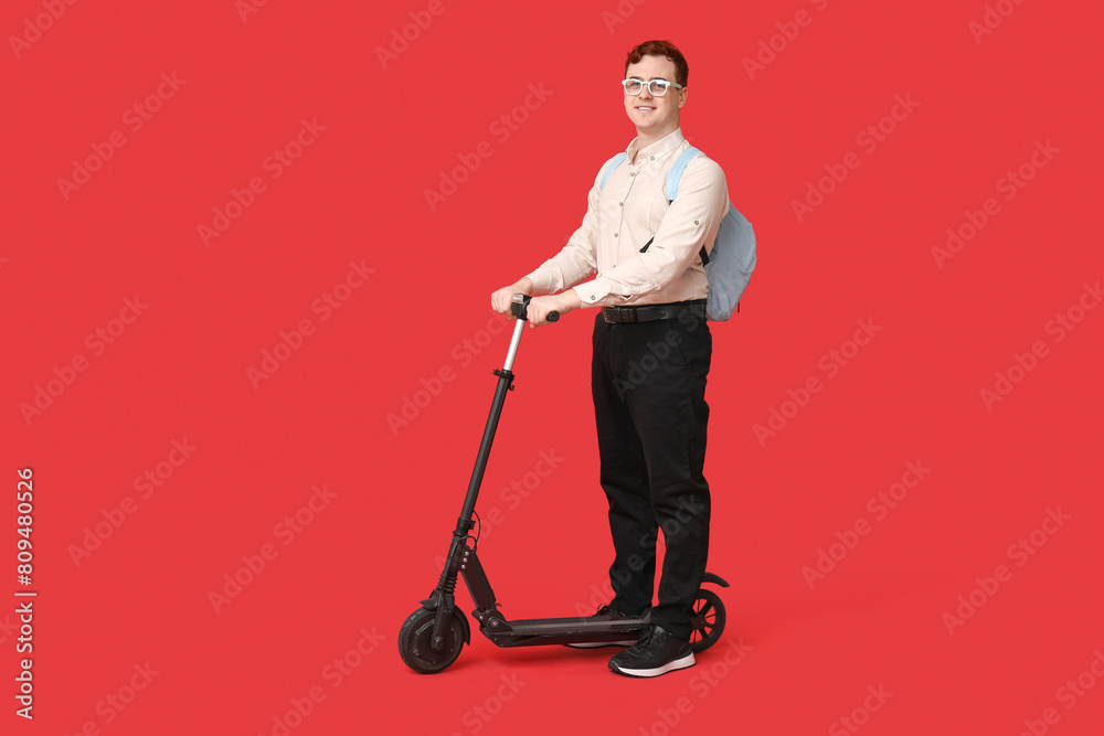 Happy male student with modern electric kick scooter on red background Happy male student with modern electric kick scooter on red background