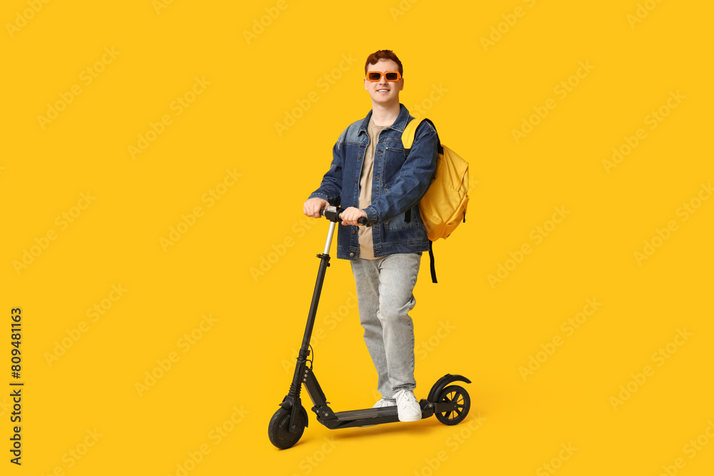 Male student with modern electric kick scooter on yellow background Male student with modern electric kick scooter on yellow background