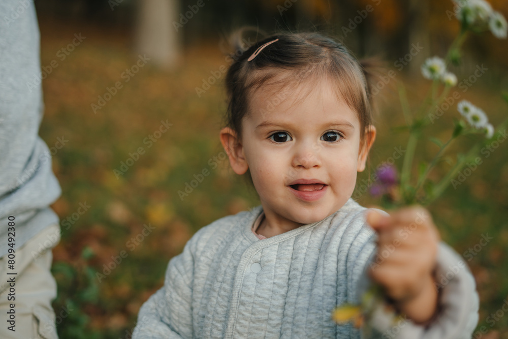 Happy little girl picking wild flowers in the meadow. Autumn seasonal outdoor activities for kids. Child explores nature. Happy little girl picking wild flowers in the meadow. Autumn seasonal outdoor activities for kids. Child explores nature.