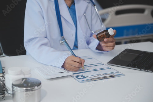 Cropped view of doctor in white coat holding bottle medication  prescribing pills to sick patient via online consultation. Family therapist recommend quality medicines. Healthcare  treatment concept