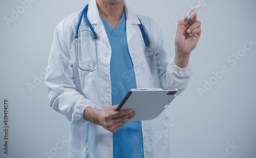 Mature male doctor with tablet pc is giving presentation. Blurred background indoors.