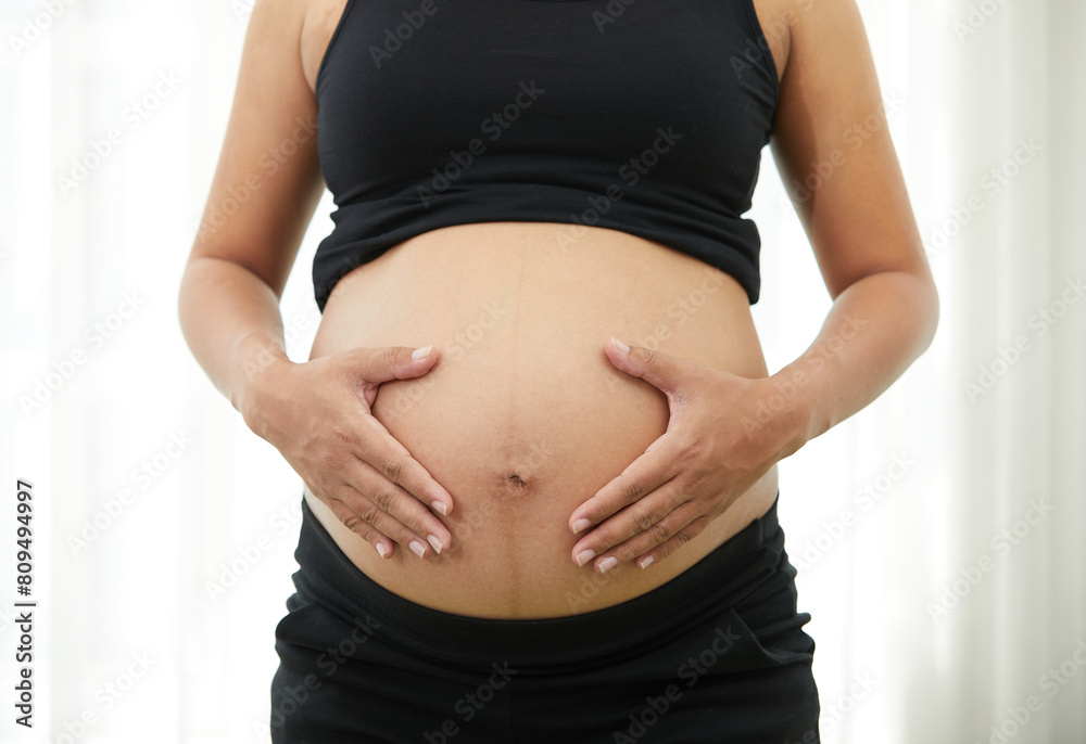 closeup pregnant woman holding hands on stomach closeup pregnant woman holding hands on stomach