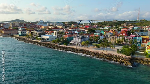 Aerial dolly above Caribbean sea water rises to orange red whtie trimmed roofs of Willemstad Curacao photo