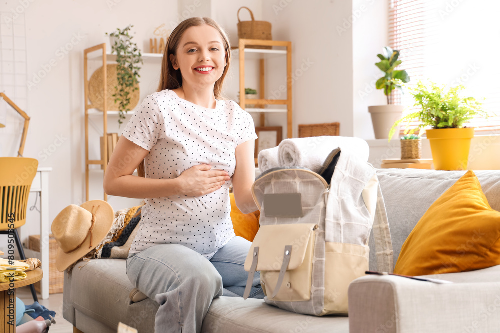 Young pregnant woman packing towels into backpack for vacation at home Young pregnant woman packing towels into backpack for vacation at home