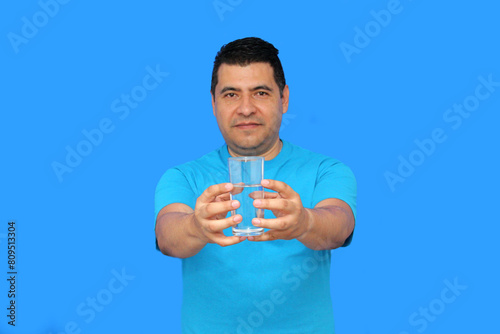 Dark-skinned Latino adult man shows his glass with still water to hydrate himself in hot weather