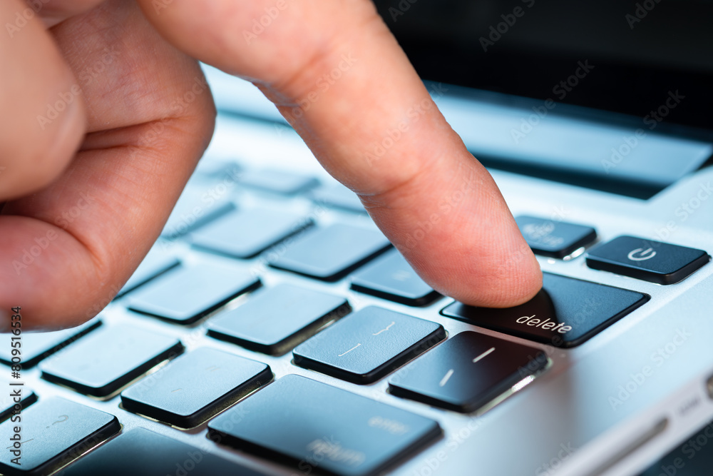 Finger of the computer user, he presses the delete button on the computer keyboard Finger of the computer user, he presses the delete button on the computer keyboard