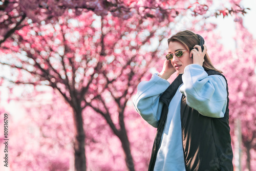 woman portrait in sunglasses with headphones blooming sakura on background