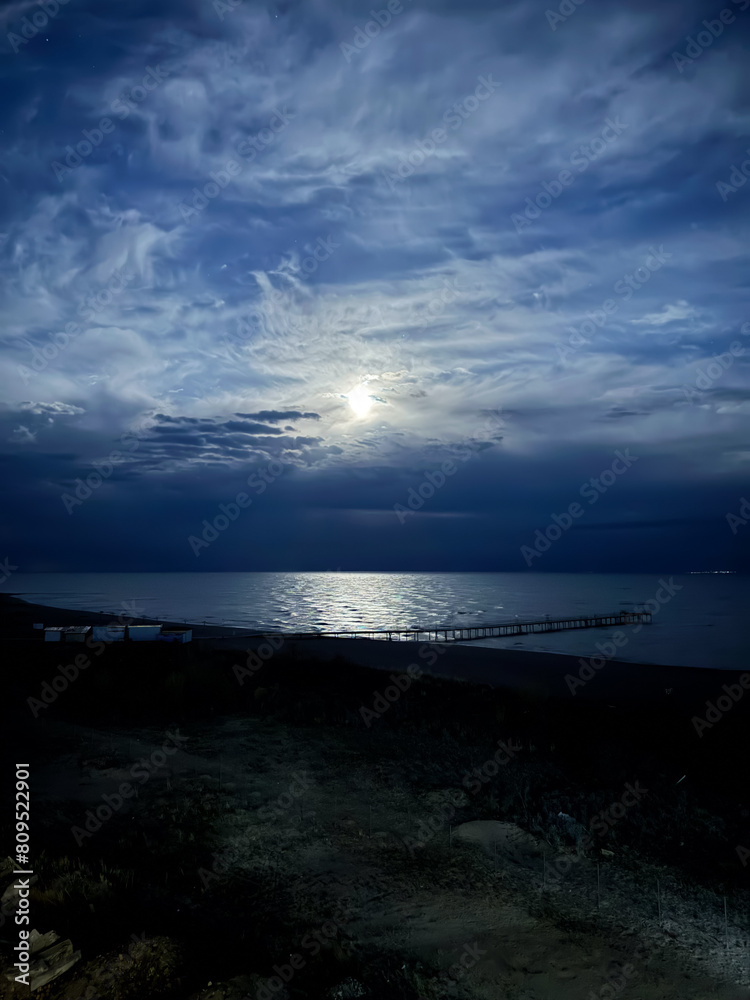 Obraz premium Moon over the lake. Full moon in the clouds. Kyrgyzstan, Lake Issyk-Kul