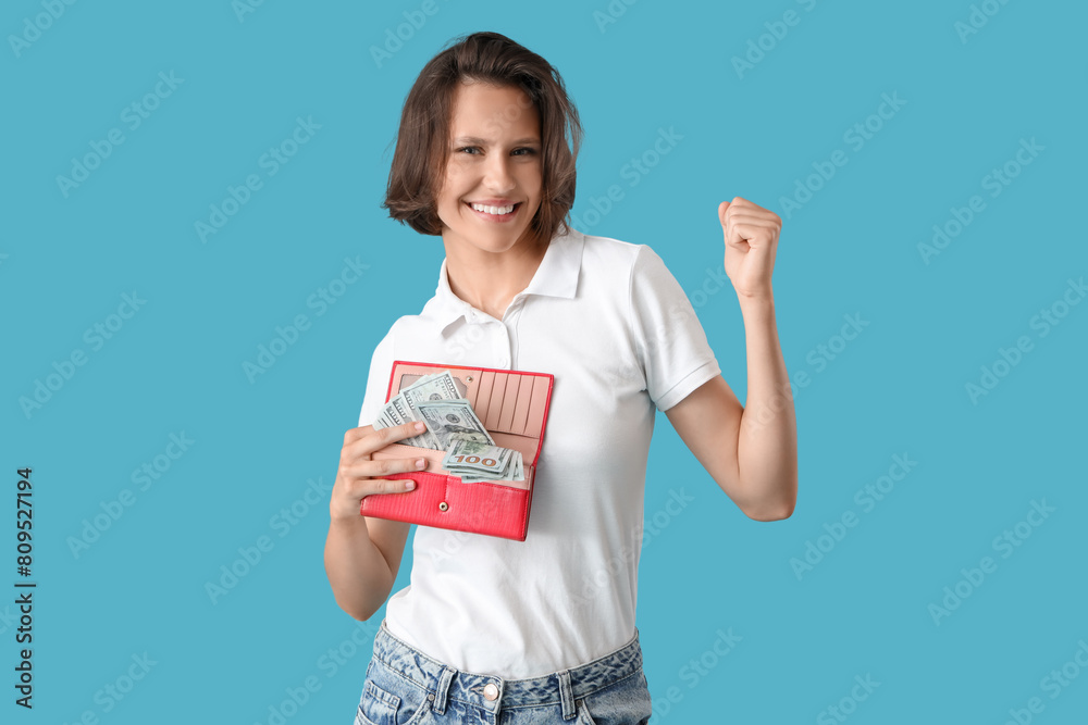 Happy young woman with money in wallet celebrating success on blue background Happy young woman with money in wallet celebrating success on blue background