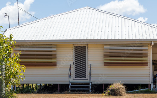 A small farmhouse with tin roof and interestingly charming window shutters, which, juxtaposed with the door make it look like a face in this rural setting in Queensland, Australia. photo
