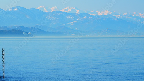 Waves Rolling On Sea A Windy Day. Blue Sky And Snow-Capped Mountains. Pan.