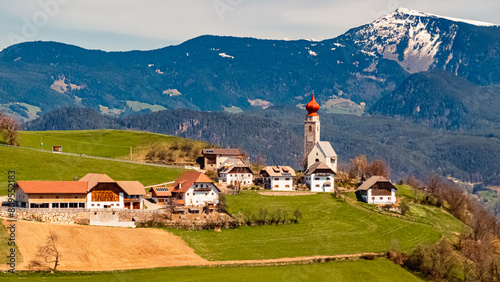 Alpine spring view with a church in the distance near Klobenstein, Ritten, Eisacktal valley, South Tyrol, Italy