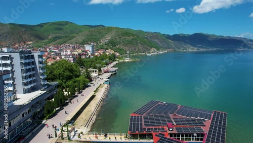 Shoreline Serenity: Lake Ohrid's Pogradec Coastline with Crystal Clear Waters and Hotels Amidst Green Trees Reflecting on the Lake's Surface photo