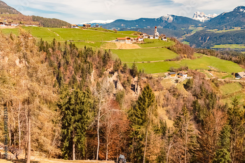 Alpine spring view with the legendary earth pyramids and a church in the distance near Klobenstein, Ritten, Eisacktal valley, South Tyrol, Italy