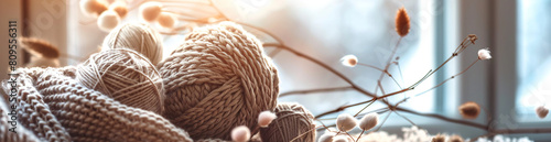 A banner featuring soft, knitted wool balls and knitting needles with natural cotton yarns in neutral tones like beige or brown. photo