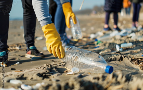Close-up of the hands of a volunteer wearing yellow gloves picking up plastic bottle waste discarded on a sandy beach. Environmental protection volunteer. Generative AI photo