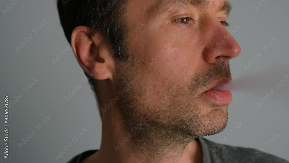 Close-up of a man smoking an electronic cigarette and exhaling smoke. Close-up of a man smoking an electronic cigarette and exhaling smoke.