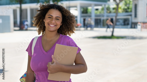 Young spanish female student with backpack infront of university