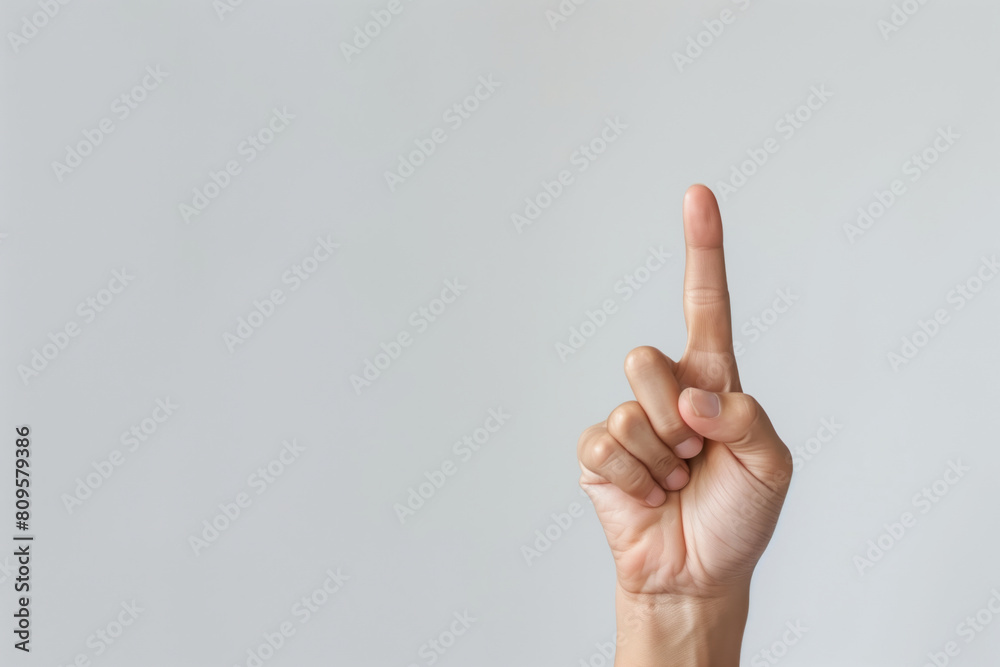 Hand showing raised index finger on plain copy space Hand showing raised index finger on plain copy space