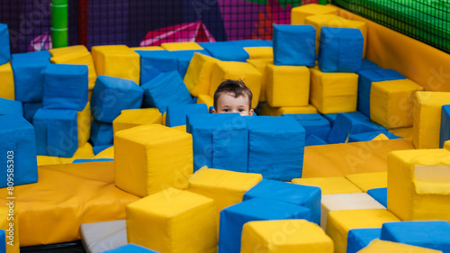 A boy child is playing in a game entertainment nursery. He plays with soft large cubes. Active pastime in the amusement park.