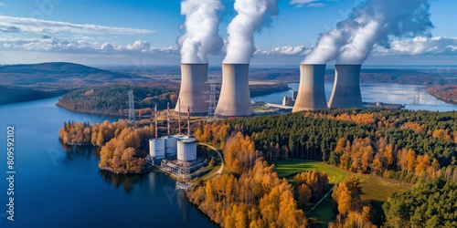 The photo shows a nuclear power plant with cooling towers and steam rising from them. There is a river and trees in the background. photo